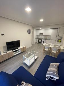a living room with a blue couch and a kitchen at Apartamento Buenavista in Oviedo