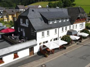 une vue aérienne sur un bâtiment blanc avec des tables et des parasols dans l'établissement Ferienwohnung Landhaus Lenneper-Führt, à Kirchhundem