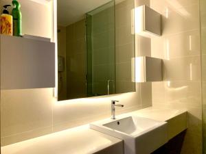 a white bathroom with a sink and a mirror at KL Gateway Residency in Kuala Lumpur