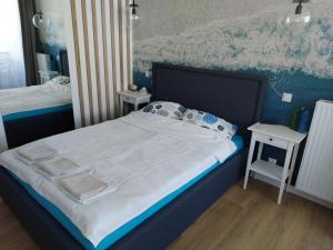 - une chambre avec un grand lit et 2 tables dans l'établissement Apartament BALTIC BLUE, à Kołobrzeg