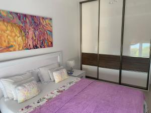 - une chambre avec un lit violet orné d'une peinture murale dans l'établissement Urban Apartment, à Petrovac na Moru