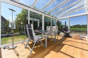 un salón acristalado con mesa y sillas en el suelo de madera en Ferienwohnungen im Haus Nordlichter, en Holtgast