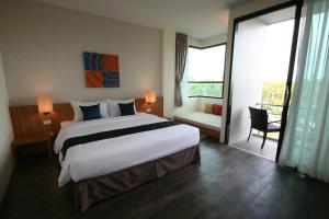 a hotel room with a large bed and a balcony at Apo Hotel in Krabi town