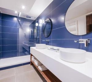 a bathroom with blue walls and two sinks and a mirror at Timhotel Le Louvre in Paris