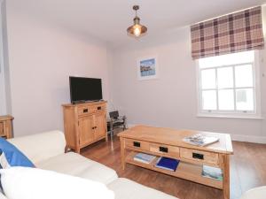 Una sala de estar con televisión y una mesa de café. en Upper 3, en Dartmouth