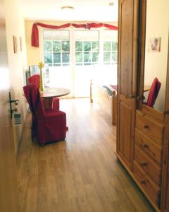 a living room with a table and red chairs at Pension & Ferienhof Glüß in Lünzen