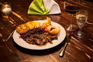 a plate of food on a wooden table with wine glasses at Restaurant & Pension Rüssel - Pub in Sangerhausen +5 photos