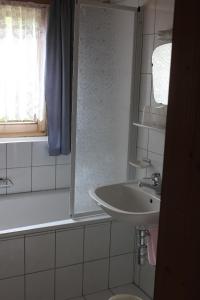 ein weißes Bad mit einem Waschbecken und einem Fenster in der Unterkunft Appartement Huber in Pertisau