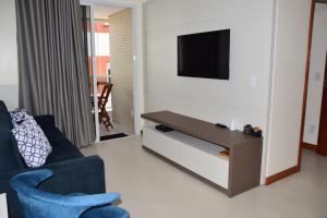 a living room with a blue couch and a tv at Apartamento a beira mar completo com churrasqueira in Florianópolis