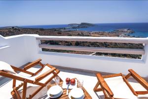 a table with chairs and a view of the ocean at Theasis Luxury Suites in Skhoinoussa