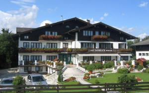 a large black and white building with cars parked in front of it at Pension Seeblick in Seebruck
