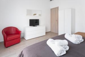 a bedroom with a red chair and a bed with towels at Bologna Suite in Bologna