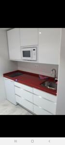 a white kitchen with a microwave and a sink at Islabeach in Isla