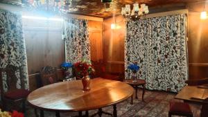 シュリーナガルにあるHouseboat New Suzanのテーブルと椅子、カーテンが備わる客室です。