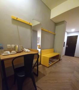 a room with a wooden table and a yellow shelf at Nite & Day Semarang - Candi in Semarang