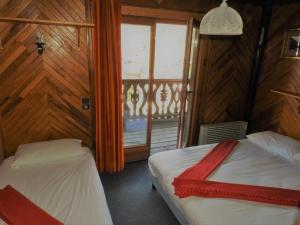 a bedroom with two beds and a window with a balcony at 1 Authentique chalet, le Mirador in Les Gets