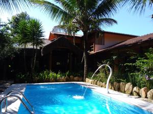 a swimming pool with a fountain in front of a house at Pousada da Terra Paraty in Paraty