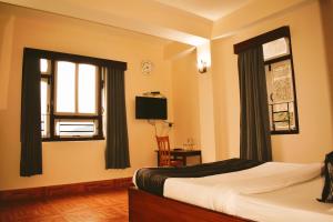 a bedroom with a bed and a window and a television at Mayel-Lyang Residency in Gangtok