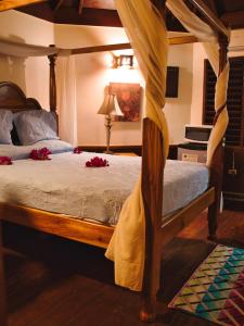 a bedroom with a canopy bed with red flowers on it at Catcha Falling Star in Negril