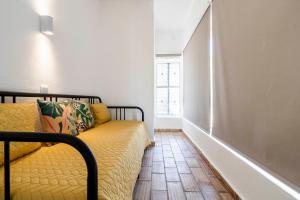 un divano giallo in una stanza con finestra di Apartamento 157, Pedras d’el Rei a Tavira
