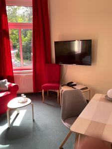 a living room with a tv and a red chair at Parkhotel Schnorr in Lutherstadt Eisleben