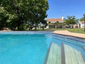 a large blue swimming pool with a house in the background at Los Manantiales Casa Rural in Alcaraz