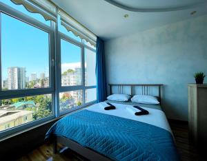 a bedroom with a bed with a large window at Мандарин in Sochi