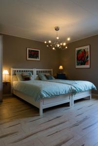 Cette chambre comprend un grand lit avec des draps bleus et un lustre. dans l'établissement Ferienhaus ROSENHOF Vulkaneifel, à Ormont