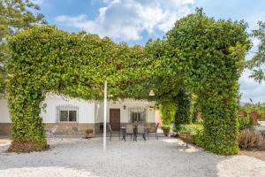 einem mit Efeu bedeckten Bogen vor einem Haus in der Unterkunft Casa rural El Polvillar / Piscina privada in Alora