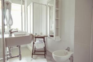 La salle de bains blanche est pourvue d'un lavabo et d'un miroir. dans l'établissement Piccolo Mondo Hotel, à Follonica