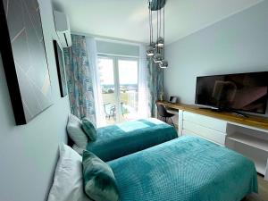 1 dormitorio con 2 camas, TV y ventana en Apartament z tarasem i widokiem na Odrę en Breslavia