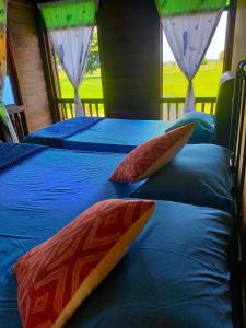 two beds in a room with blue and red pillows at Che'Pa Village Langkawi in Kuah