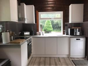 a kitchen with white cabinets and a window at Fox Lodge Traditional Log Cabin in Dunoon