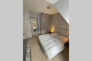 Un dormitorio con una cama grande con sábanas blancas. en Les oiseaux T2, en Le Mont-Dore