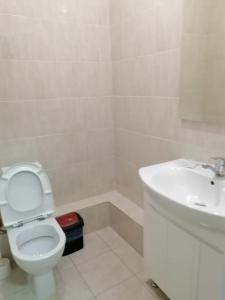 a bathroom with a white toilet and a sink at Apart Hotel 36 этаж in Astana
