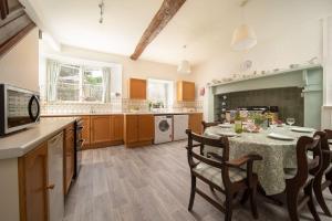 eine Küche mit einem Tisch und Stühlen in einer Küche in der Unterkunft Diana's Cottage in Braunton