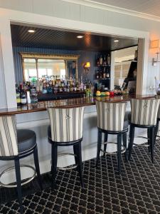 a bar with three bar stools in a room at Cape Arundel Inn and Resort in Kennebunkport