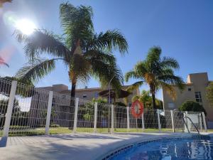 a fence next to a swimming pool with palm trees at Indo Loma Sancti Petri in Chiclana de la Frontera