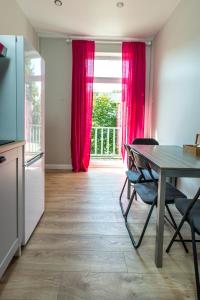 een keuken met een tafel en een raam met rode gordijnen bij à la fontaine in Druskininkai