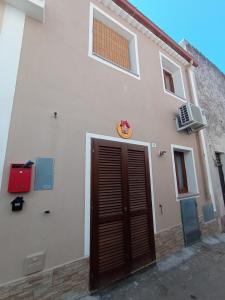 - un bâtiment blanc avec une porte marron et une fenêtre dans l'établissement B&B la piccola maison, à Ploaghe