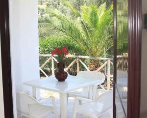 una mesa blanca y sillas con un jarrón con flores rojas en Village Valle D'Oro ApartHotel, en San Menaio
