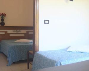 1 dormitorio con cama, mesa y espejo en Village Valle D'Oro ApartHotel, en San Menaio