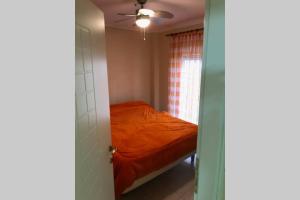 a bedroom with an orange bed and a ceiling fan at Aris Apartment in Neo Rysio in Néon Rýsion