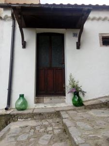 two green vases sitting outside of a house with a door at Casa borghetto in Cancellara