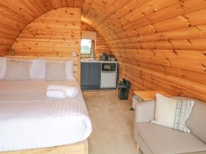 a bedroom with two beds and a couch in a log cabin at Pod 6 in Ballymoney