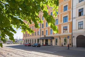 un edificio en una calle con coches aparcados delante en Metropole Hotel by Semarah en Riga