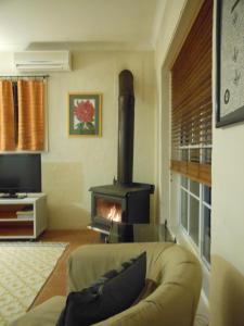 a living room with a couch and a wood stove at Merrimeet Cottages in Bright