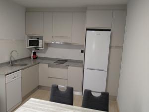 eine Küche mit 2 Stühlen und einem weißen Kühlschrank in der Unterkunft APTMUNDO BAJAMAR - Precioso apartamento Planta baja y patio in Puerto de Sagunto