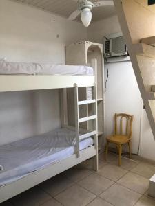 a room with two bunk beds and a chair at Charmosa Casa pertinho do morro do céu in Laguna