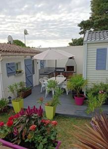 un patio con mesa, sombrilla y flores en l'IOasis, location saisonnière ouverte toute l'année sur l'Ile d'Oléron en Dolus d'Oléron